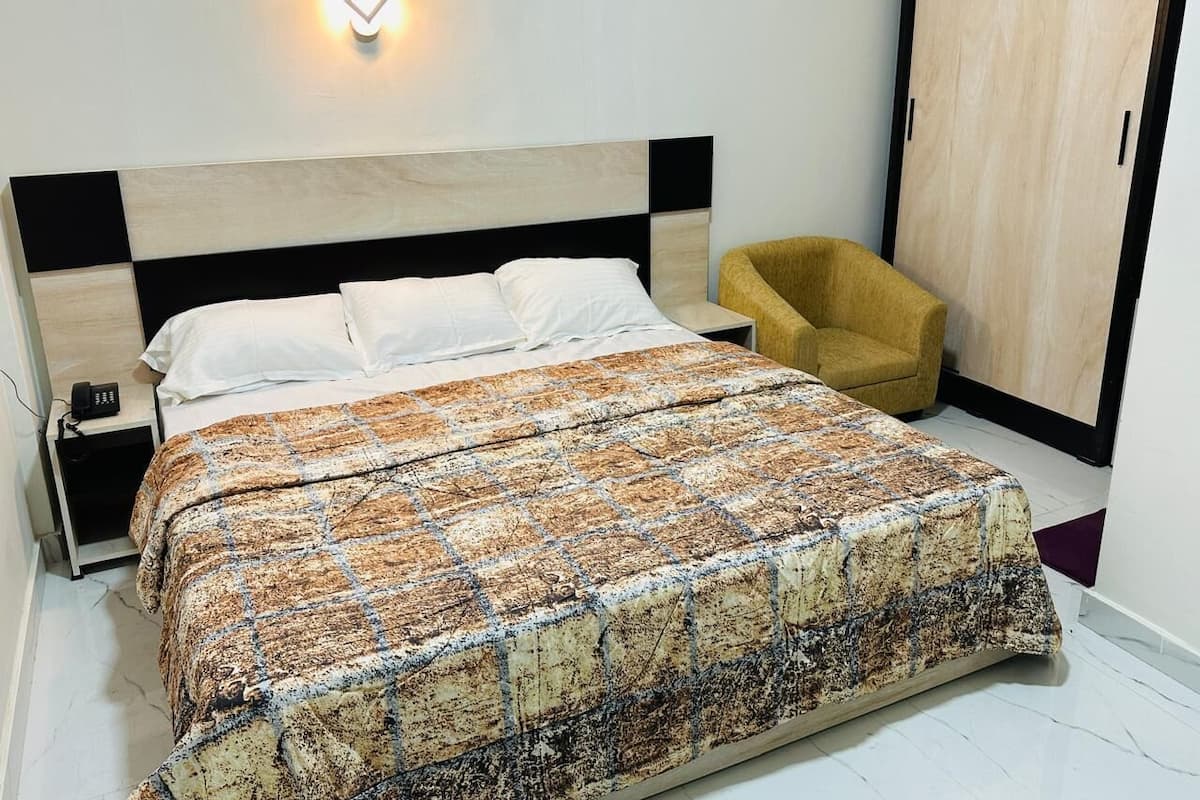 A bedroom with a bed, a nightstand, a chair, and a wardrobe.