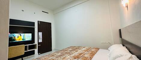 Una habitación de hotel con cama, televisión, escritorio y armario.