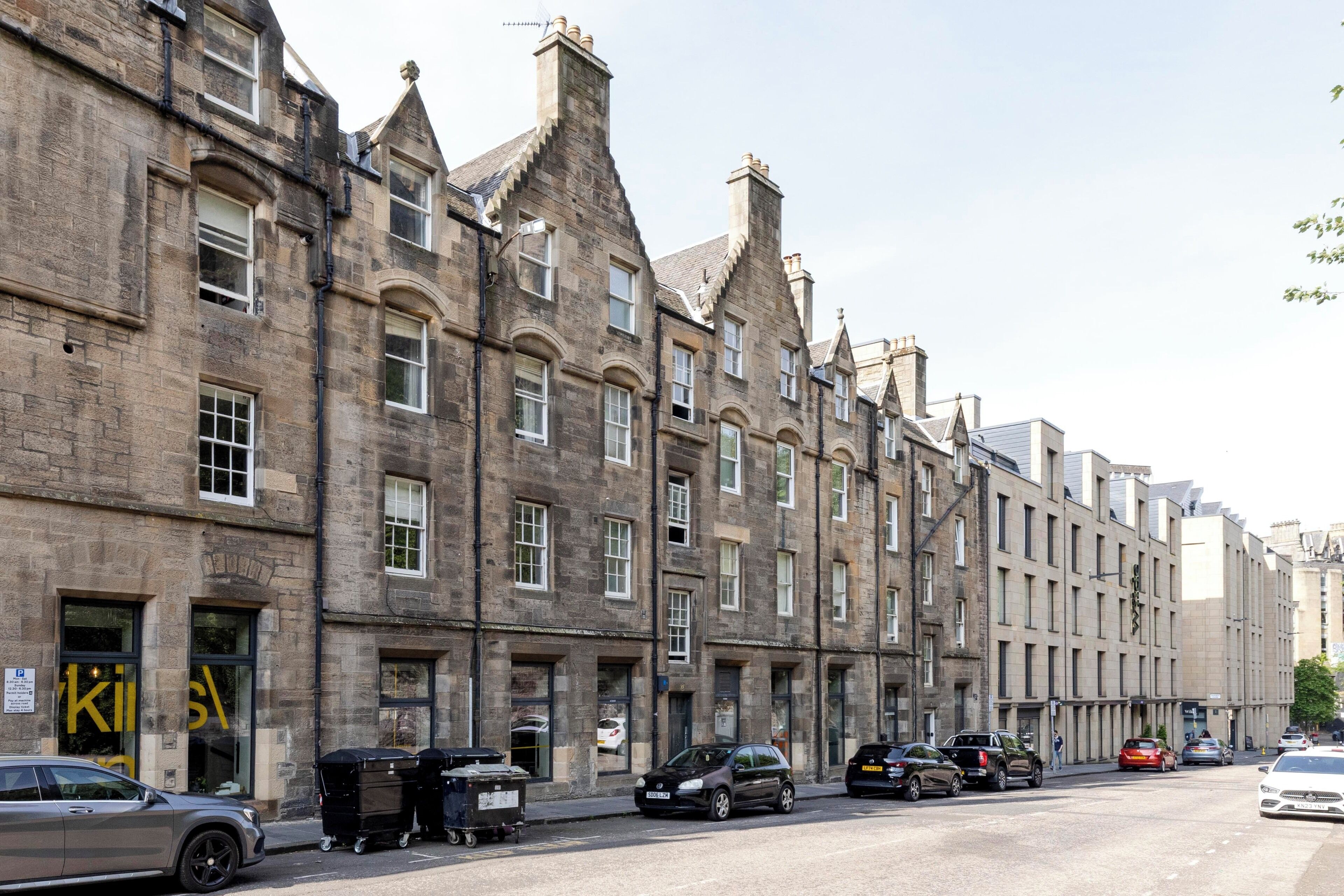 A row of historic stone buildings with uniform windows and a central entrance.