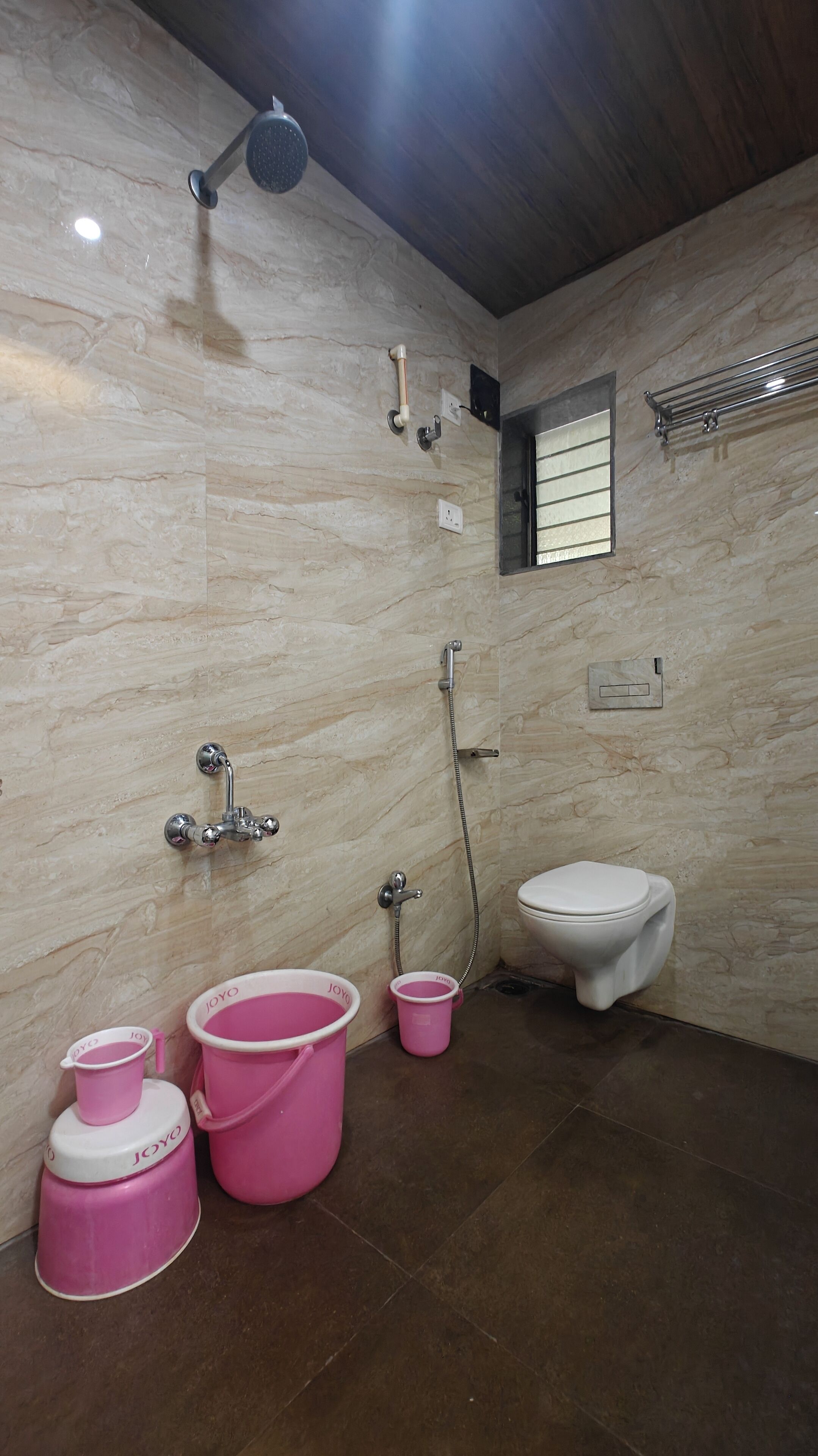 Un baño con ducha, inodoro y cubos rosas.