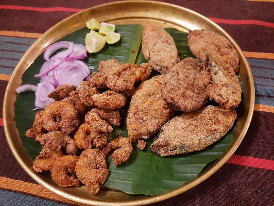Une assiette de fritures, garnie d’oignons en tranches et de quartiers de citron.