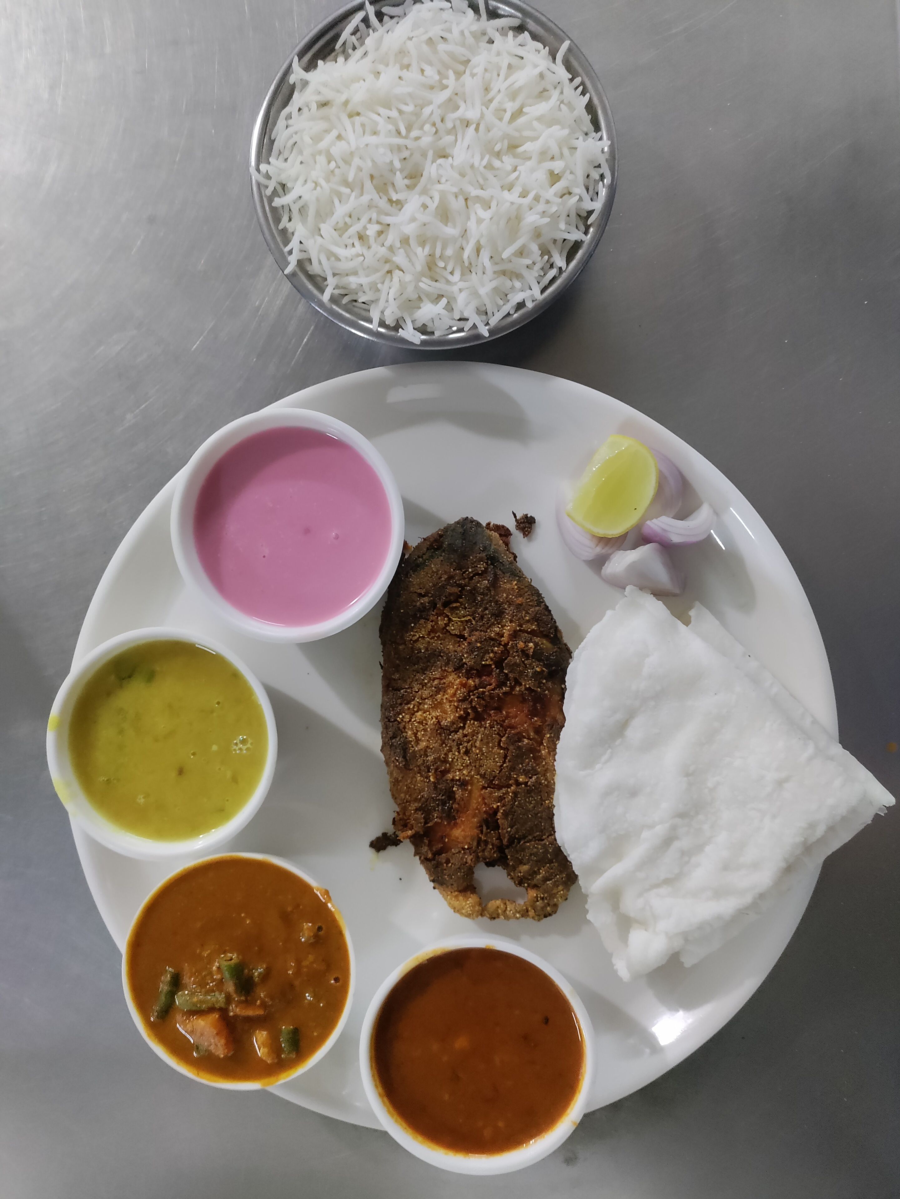 A plate with rice, a piece of fish, and four different types of curry.