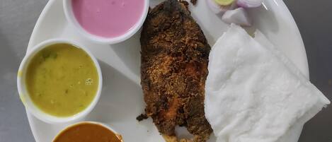 A plate with rice, a piece of fish, and four different types of curry.