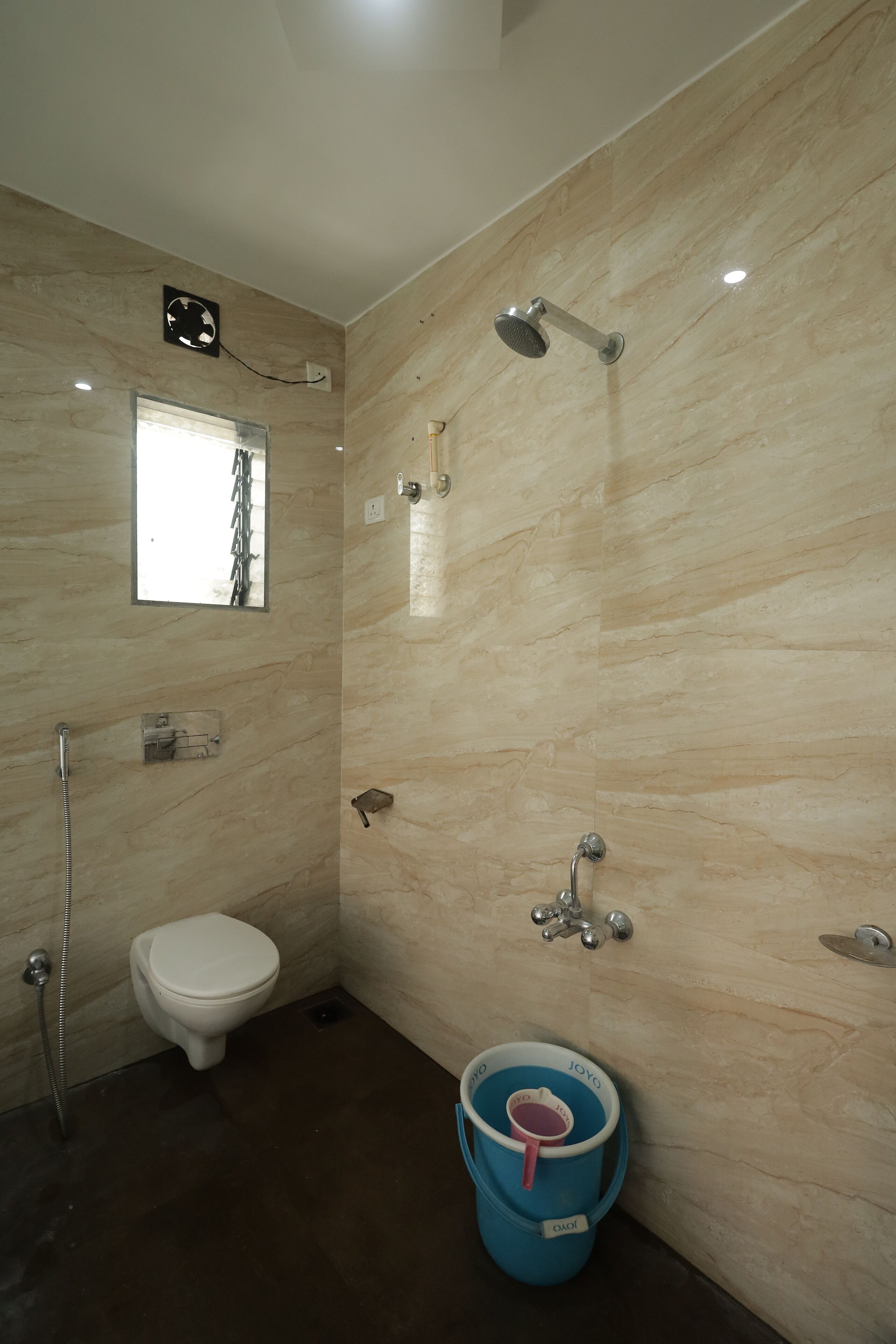 A bathroom with a toilet, shower, and a bucket.