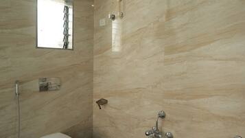 A bathroom with a toilet, shower, and a bucket.