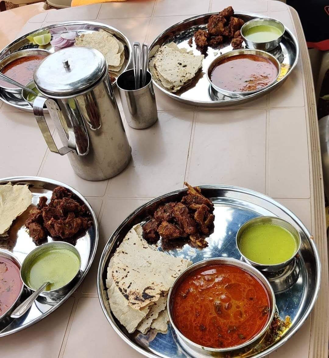A table with multiple metal plates containing various dishes, including flatbreads, meat, and different types of sauces.