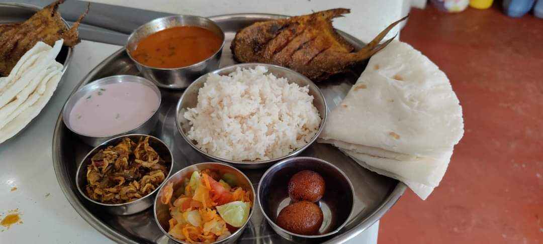A meal with rice, fish, and various side dishes on a metal plate.