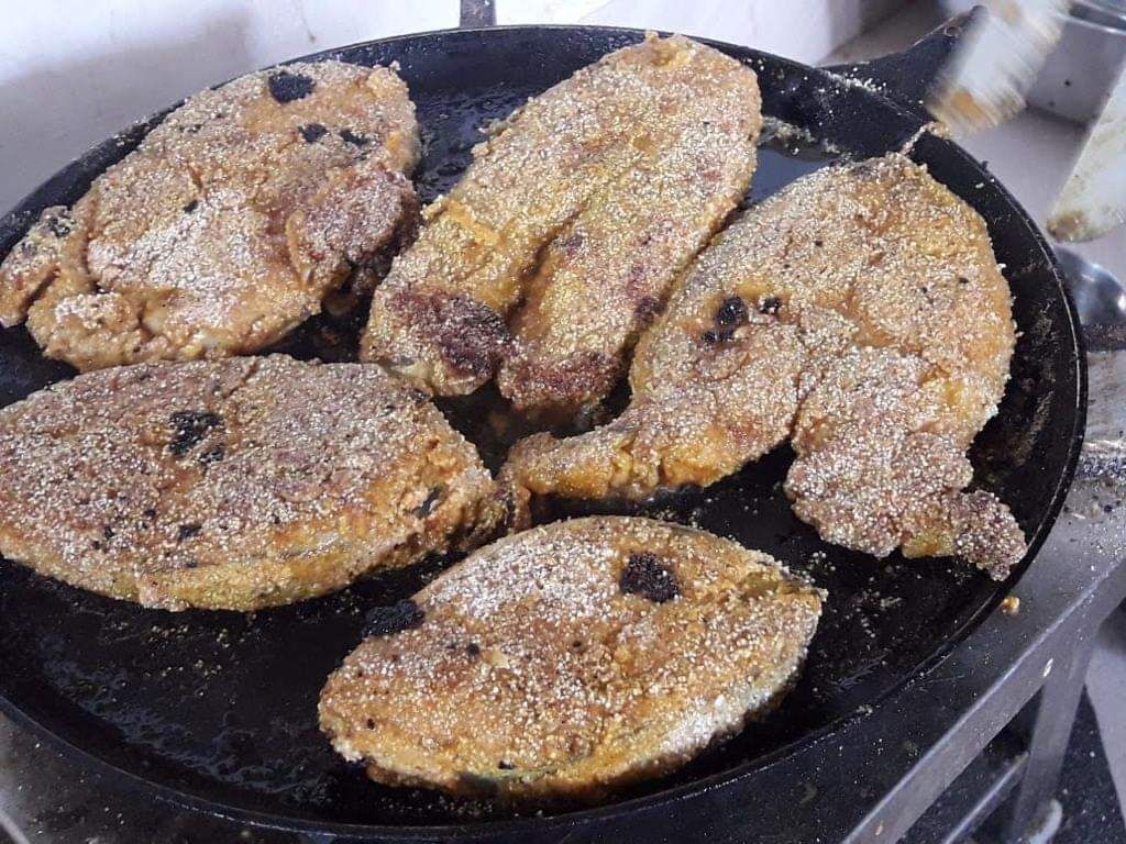 A skillet with several pieces of food being cooked.