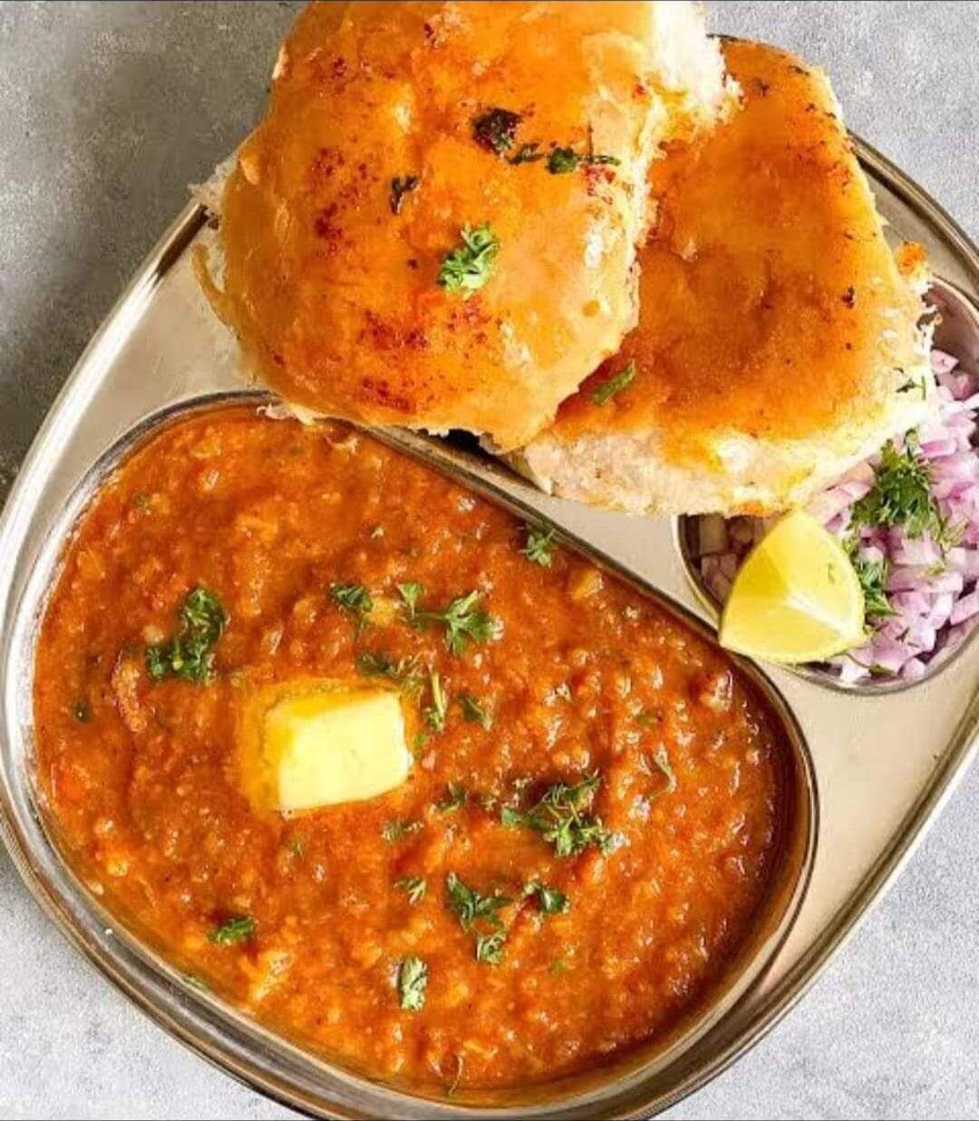 A meal consisting of a bowl of lentil soup garnished with butter and herbs, accompanied by two pieces of bread.