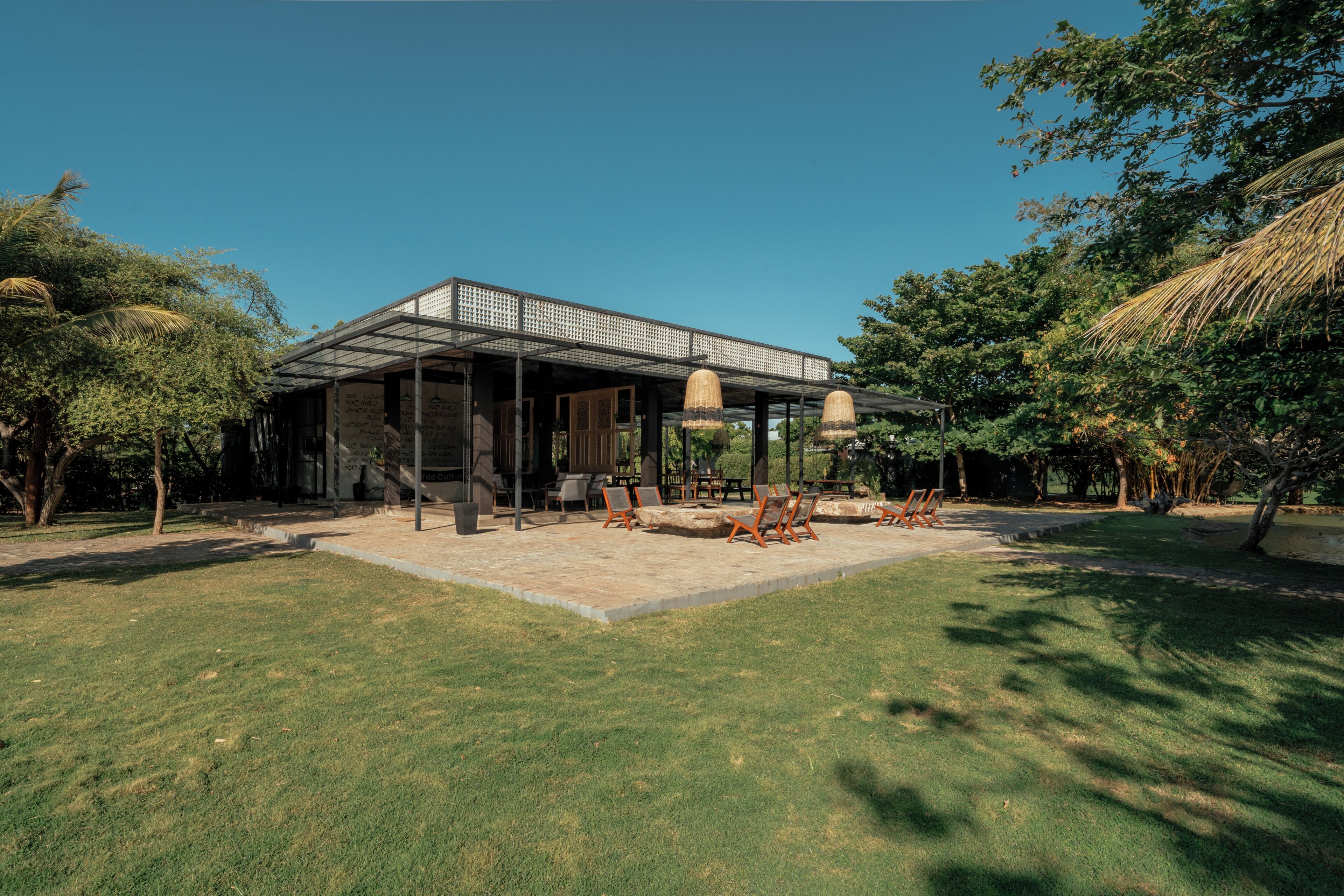 A modern house with a covered patio area, outdoor seating, and a well-maintained lawn.