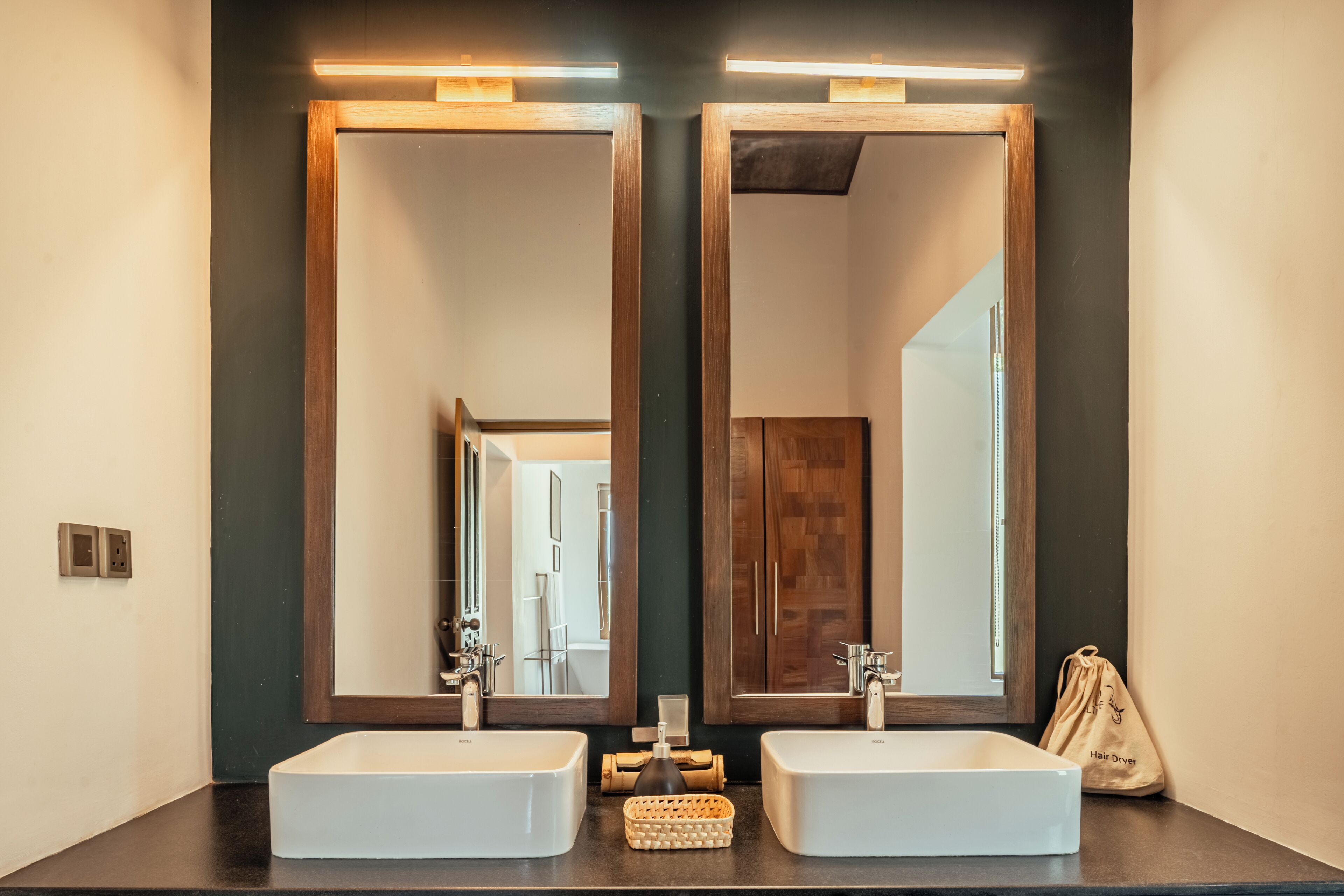 Une salle de bain avec deux lavabos blancs, des meubles en bois et un miroir avec un cadre en bois.