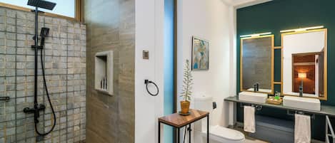 A modern bathroom with a shower, toilet, and dual sinks.