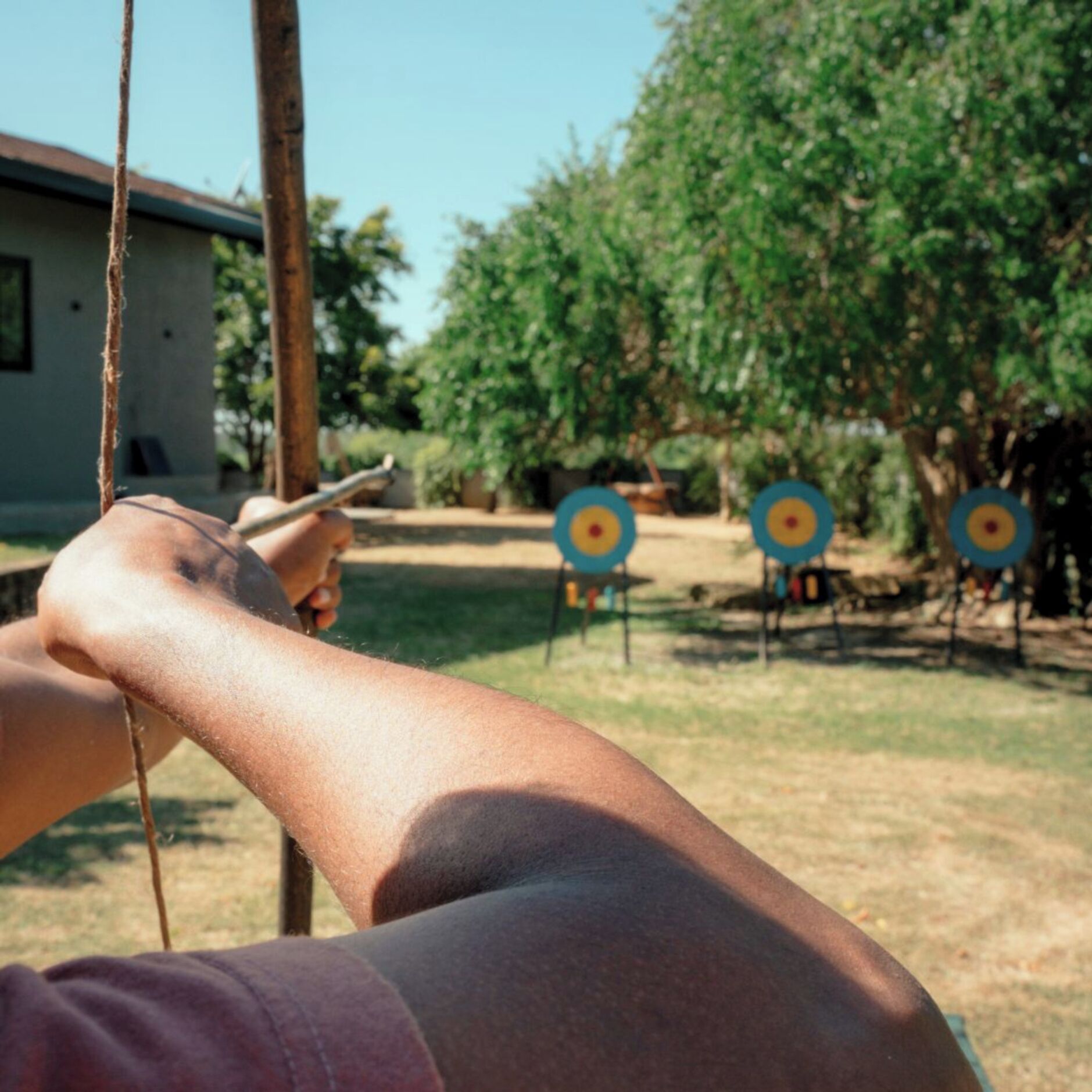 A person aiming at an archery target in an outdoor setting.