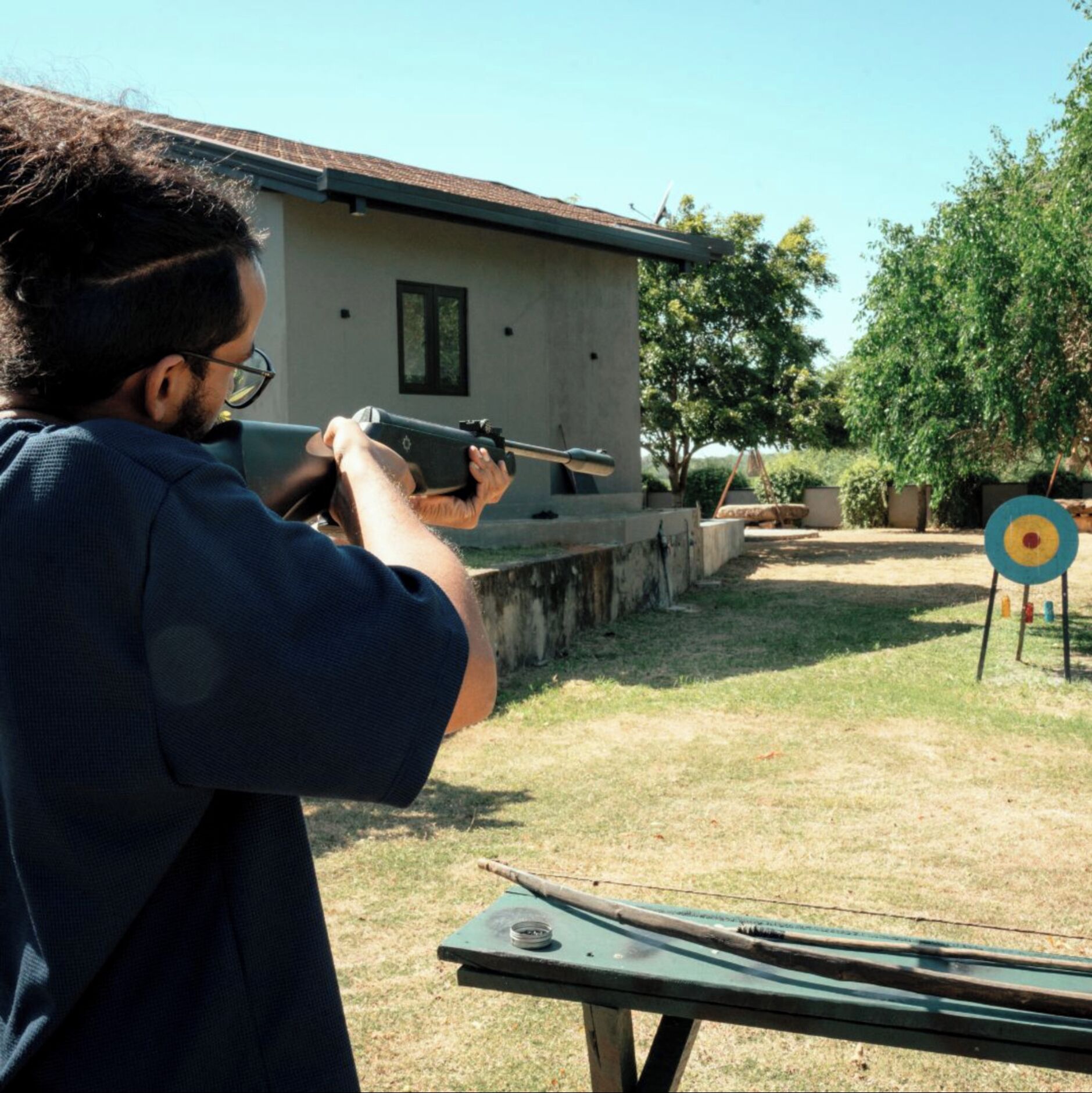 A person aiming a rifle at an outdoor target.