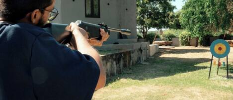 A person aiming a rifle at an outdoor target.