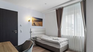 Moderni hotellihuone, jossa on sänky, työpöytä ja tuoli.