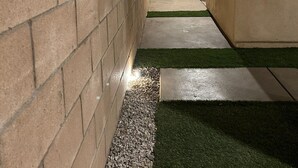 A narrow outdoor corridor with a brick wall on one side and a building on the other.