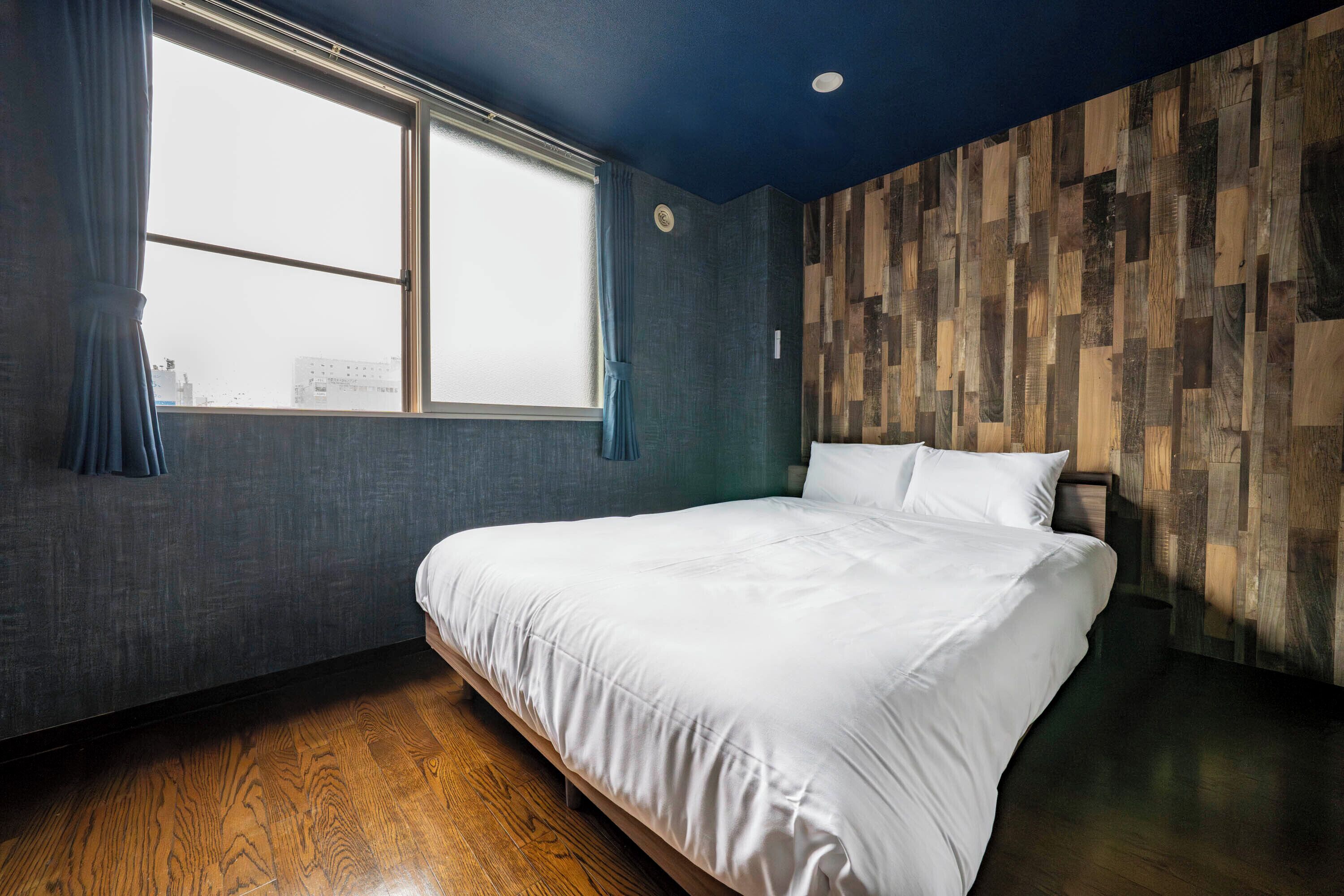 Une chambre dotée d’une grande fenêtre, d’un lambris en bois et d’un lit recouvert de linge de lit blanc.