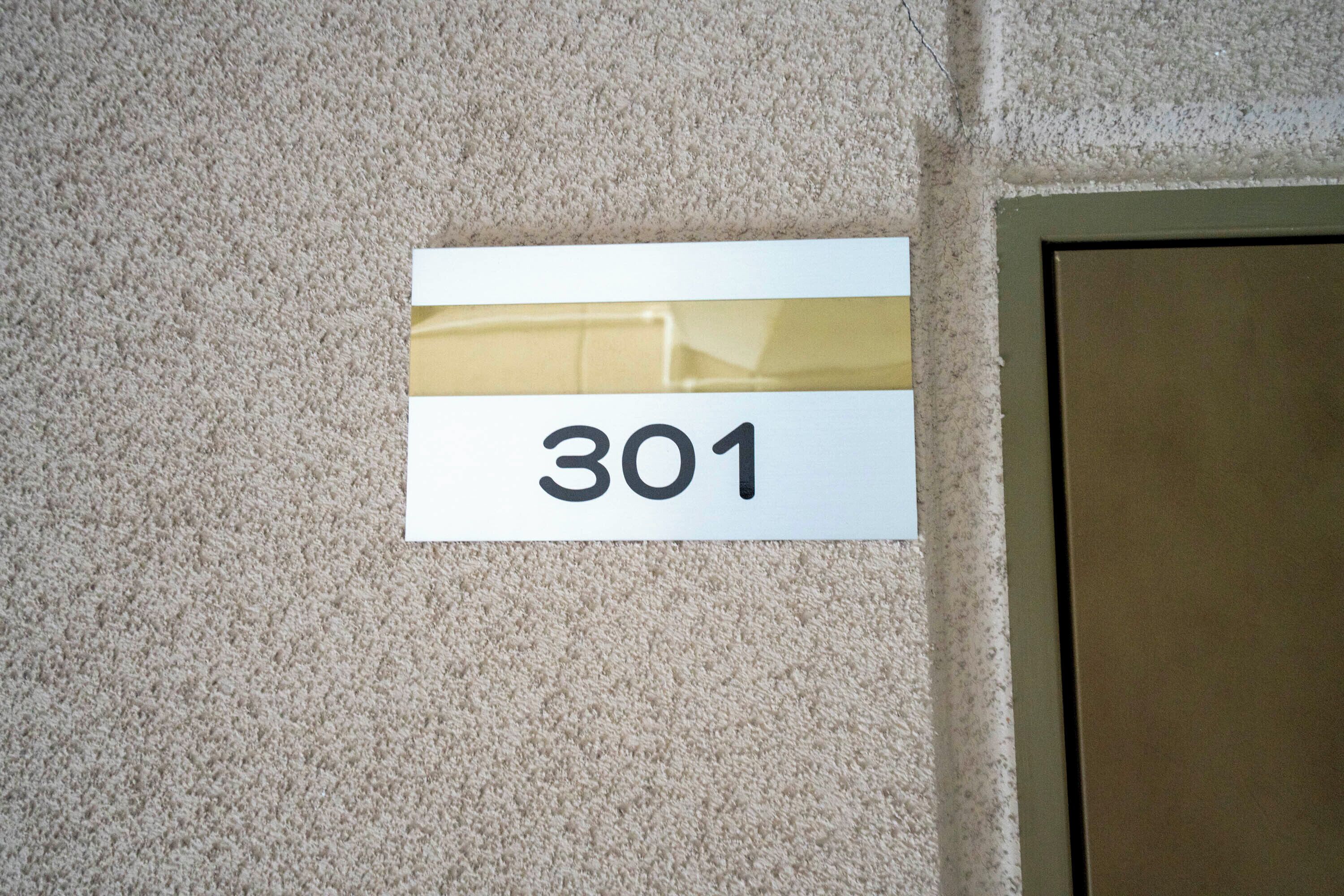 Une plaque indiquant le numéro de chambre, 301, sur un mur à texture.