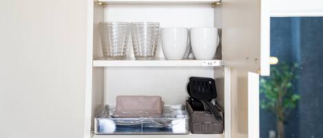 Ein Küchenschrank mit Geschirr, Gläsern und Besteck.
