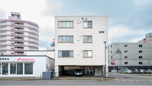 Un immeuble à plusieurs étages abritant au rez-de-chaussée une concession Honda, une entrée de garage et un panneau indiquant l’interdiction de se garer.