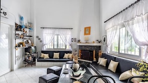 A modern living room with a black sofa, a glass coffee table, and a fireplace.