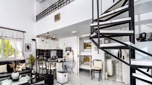 A spacious living area with a modern kitchen, a dining area, and a black spiral staircase.