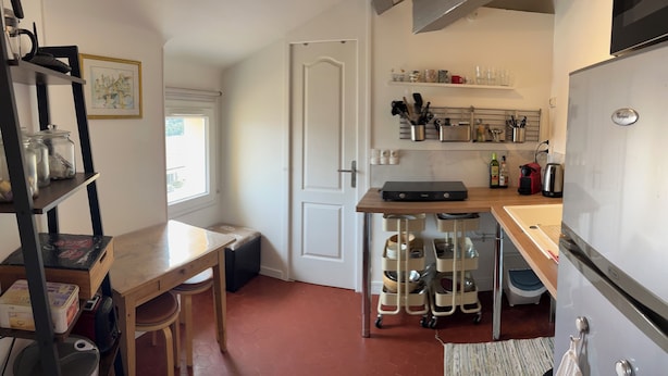 Une cuisine compacte avec une table en bois, une machine à café et un réfrigérateur.