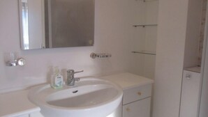 A bathroom with a white sink, mirror, and two shelves. - Quiet studio, balcony with lake view, parking, near the spa, close to the center (aix les bains)