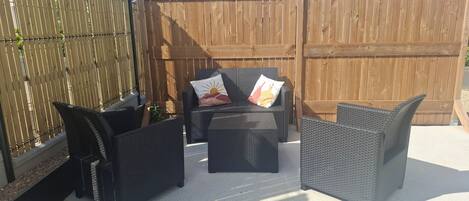 An outdoor patio area with wicker furniture and a wooden fence.