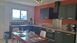 A compact kitchen with a dining area, featuring a window, modern appliances, and a view of the outside.