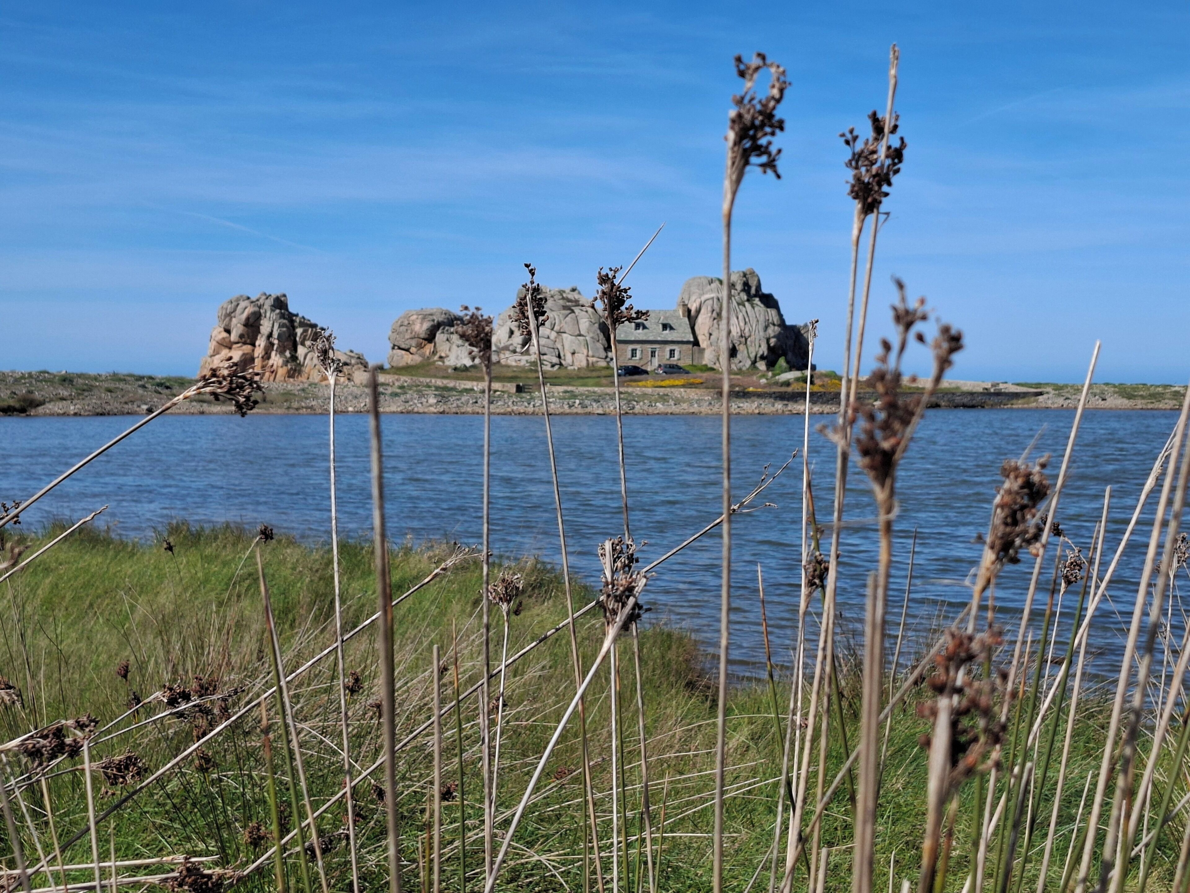 Un paysage côtier avec un promontoire rocheux et un bâtiment.