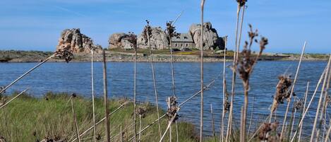 Un paysage côtier avec un promontoire rocheux et un bâtiment.