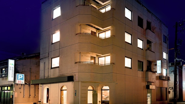 Un edificio a più piani con un cartello ben visibile che riporta "Happiness Inn" in alto.