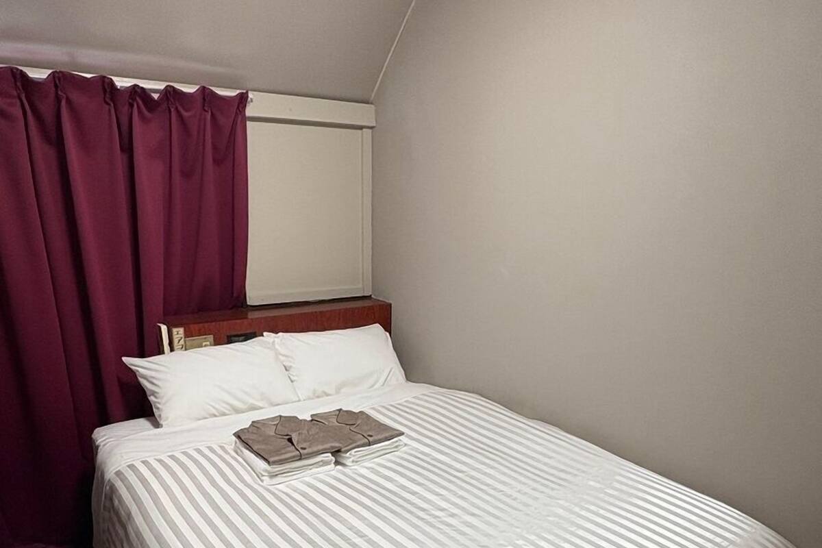 Une chambre d’hôtel avec un lit, une fenêtre avec des rideaux et un sol recouvert de moquette.