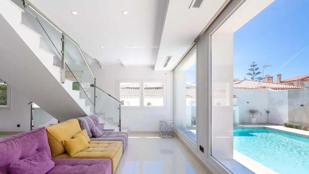 Un interior moderno con un conjunto de sofás, una escalera y vistas a una piscina.