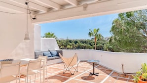 Eine Terrasse im Freien mit einem weißen Tisch, Stühlen, einer Couch und einem kleinen runden Tisch.