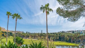 Ein Golfplatz mit Palmen, einem Teich und Blick auf eine Wohngegend im Hintergrund.