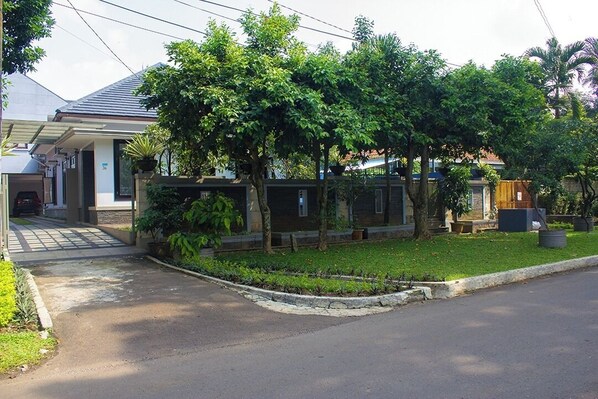 A residential area with houses, a paved driveway, and well-maintained lawns.