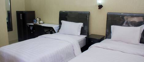 A hotel room with two beds, a desk, and a chair.