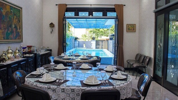 Un área de comedor con vista a la piscina, un cuadro en la pared y un mueble decorativo.