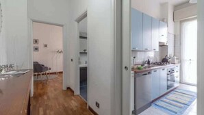 A modern kitchen with grey cabinets, a wooden countertop, and a large window. - House Romana Center (Milano)