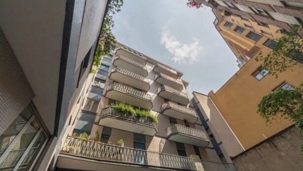 A multi-story residential building with balconies, a flat roof, and a clear sky. - House Romana Center (Milano)