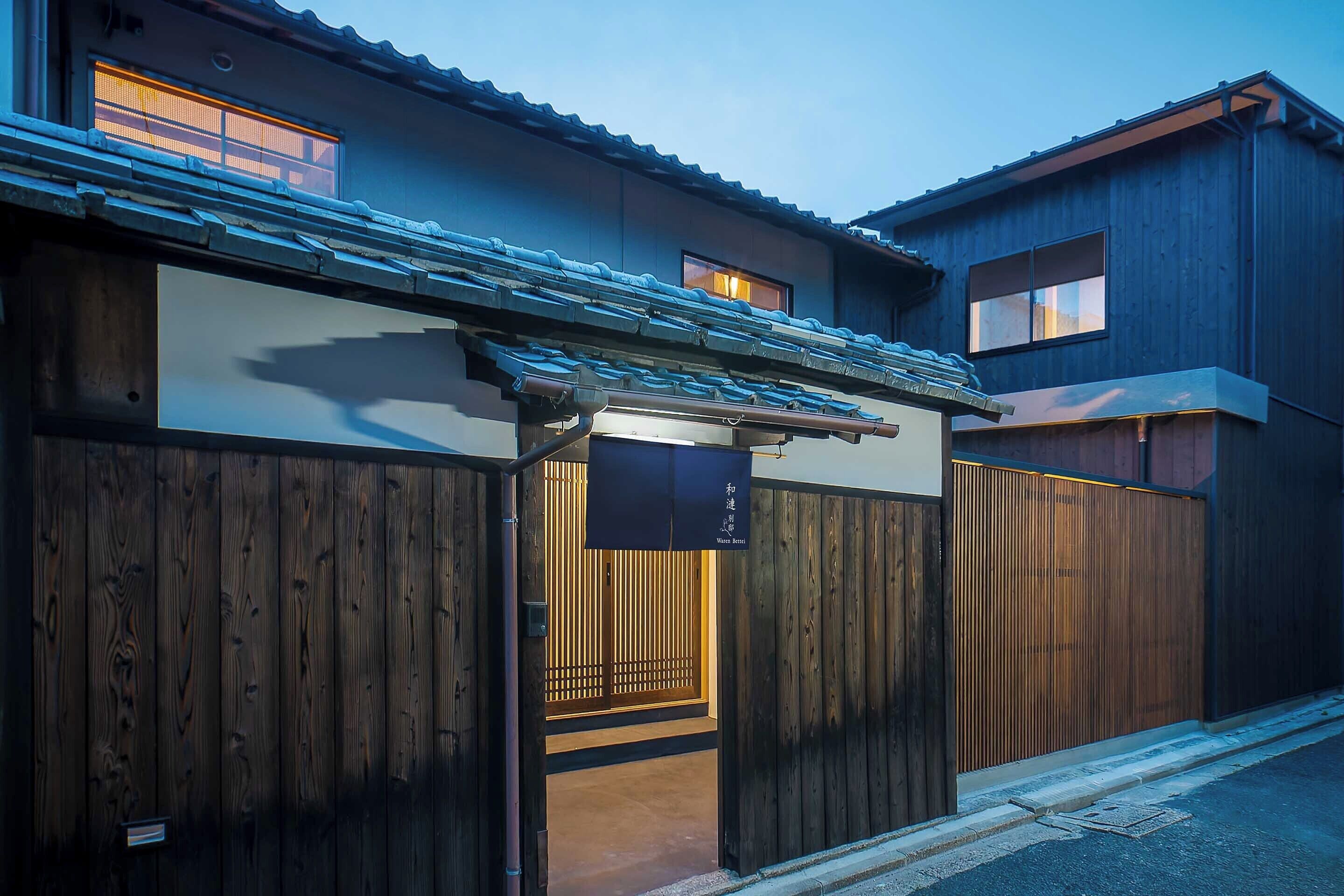 A traditional Japanese house with a wooden gate, a tiled roof, and a small entrance.