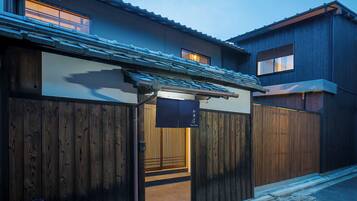 A traditional Japanese house with a wooden gate, a tiled roof, and a small entrance.