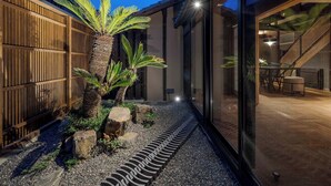 A modern building with a glass facade, a wooden fence, and a palm tree in the courtyard. - Waren Bettei Machiya House (Kyoto)
