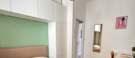 A bedroom with a bed, a desk, and a hanging light fixture.