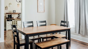 A dining area with a wooden table and chairs, a ceiling fan, and a view of a kitchen and living area through an open door. - Minutes from Maxwell AFB, this historic 3BR feels more like home than a rental. Guests love the quiet street, thoughtful touches, and a host who makes every stay easy. (Montgomery)