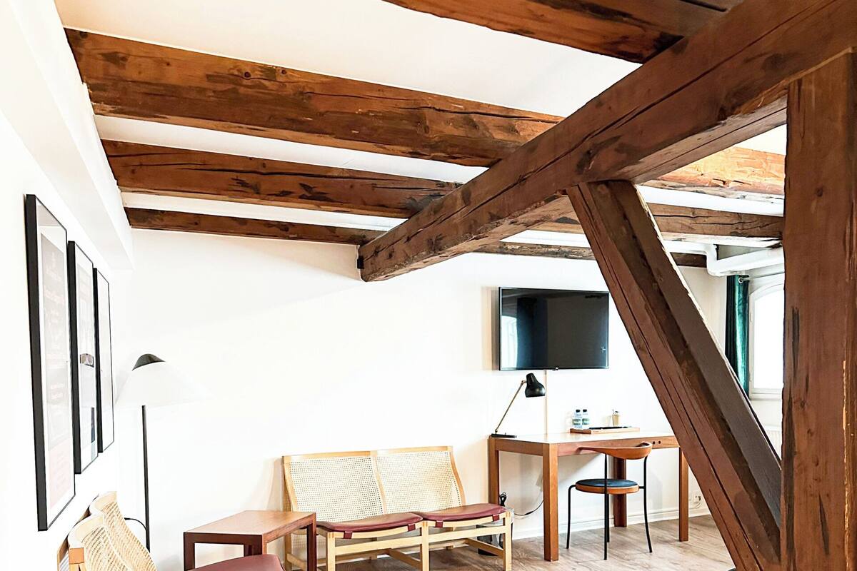 A room with wooden beams, a wooden bench, a table, and a chair.