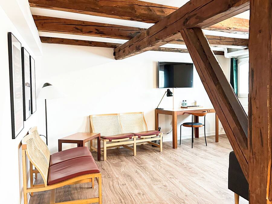 A room with wooden beams, a wooden bench, a table, and a chair.